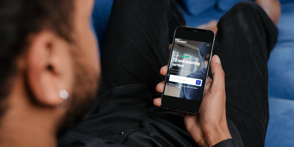 Man booking TV wall mounting on the Housekeep website through a smart phone