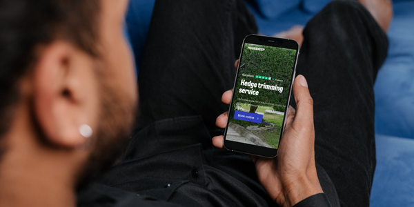 Man booking hedge trimming services on a smart phone through the Housekeep website
